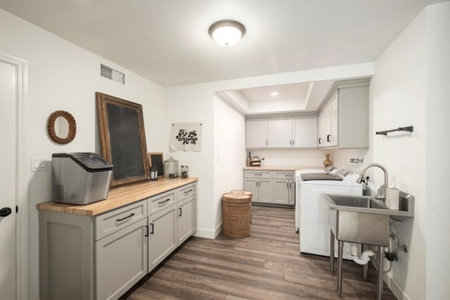 laundry area featuring sink, cabinets, washing machine and clothes dryer, and dark hardwood / wood-style flooring