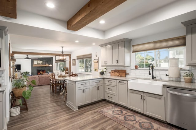 kitchen with dishwasher, kitchen peninsula, sink, plenty of natural light, and tasteful backsplash