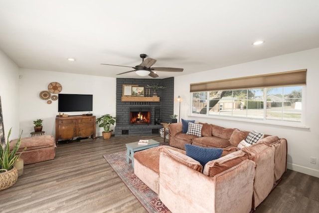 living room featuring ceiling fan, wood-type flooring, and a brick fireplace