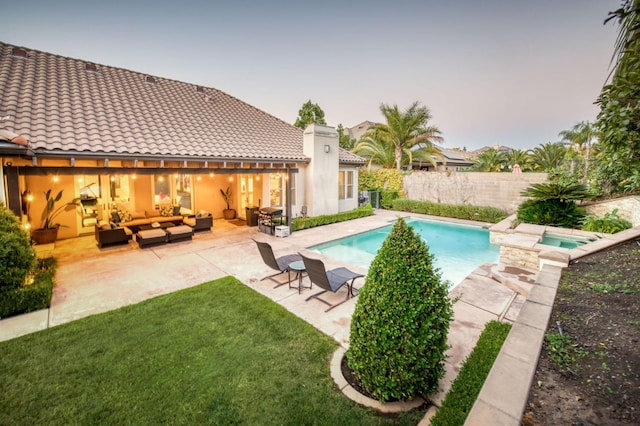 pool at dusk with an outdoor hangout area, a patio, a lawn, and an in ground hot tub