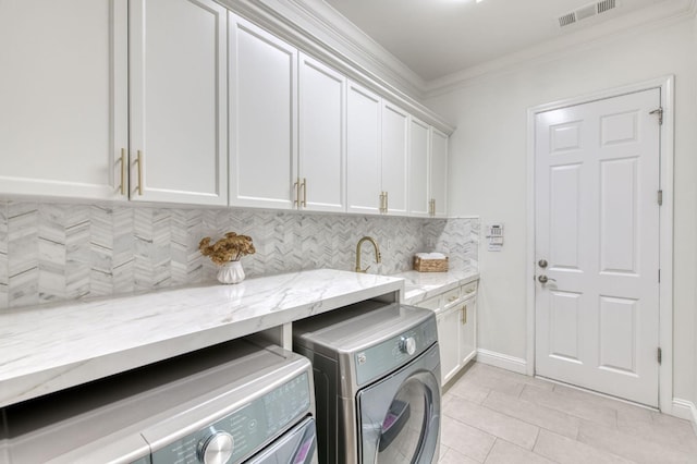 washroom with washing machine and dryer, sink, ornamental molding, cabinets, and light tile patterned floors