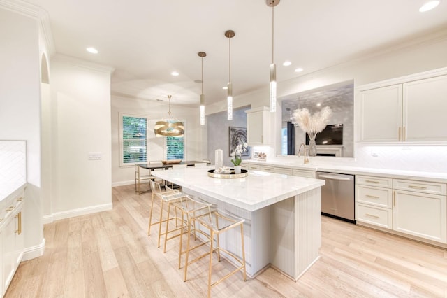 kitchen with dishwasher, a center island, pendant lighting, crown molding, and light hardwood / wood-style flooring