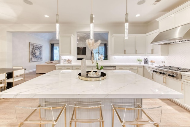 kitchen featuring a breakfast bar, white cabinetry, decorative light fixtures, and light stone counters