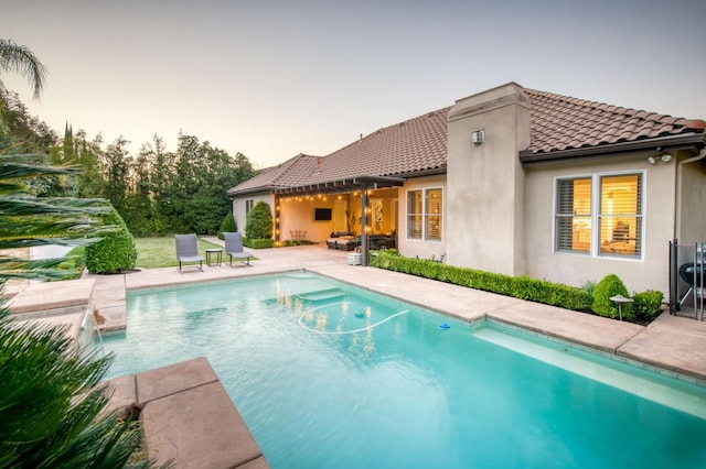 pool at dusk with a patio area