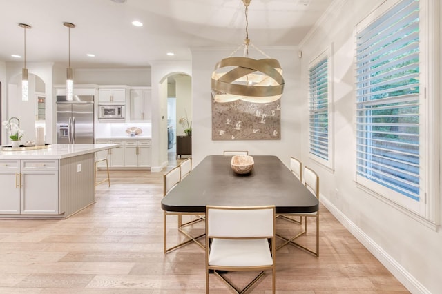 dining room with sink, a chandelier, crown molding, and light hardwood / wood-style floors