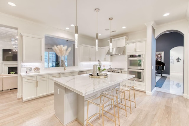 kitchen featuring stainless steel double oven, a kitchen island, ventilation hood, light wood-type flooring, and white cabinetry