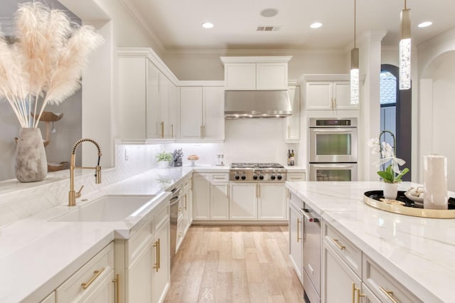 kitchen with white cabinetry, wall chimney exhaust hood, appliances with stainless steel finishes, and sink