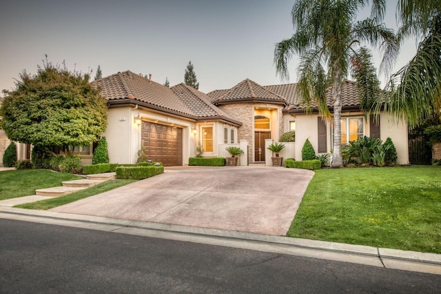 mediterranean / spanish-style home with a yard and a garage