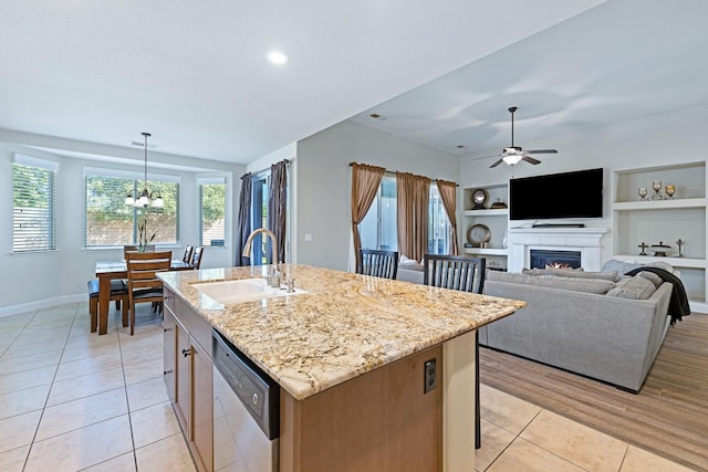 kitchen with dishwasher, a center island with sink, sink, decorative light fixtures, and built in features