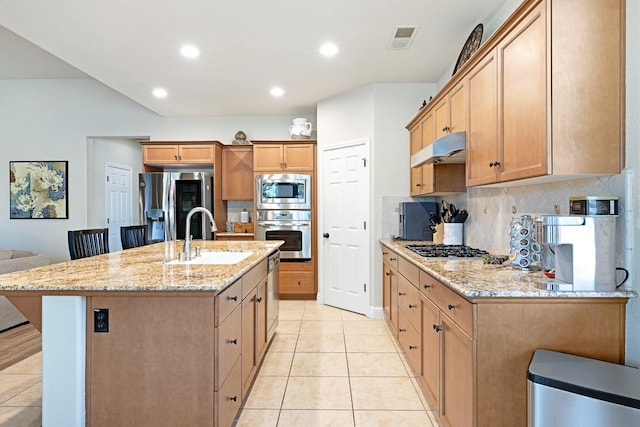 kitchen with light stone counters, an island with sink, appliances with stainless steel finishes, light tile patterned flooring, and sink