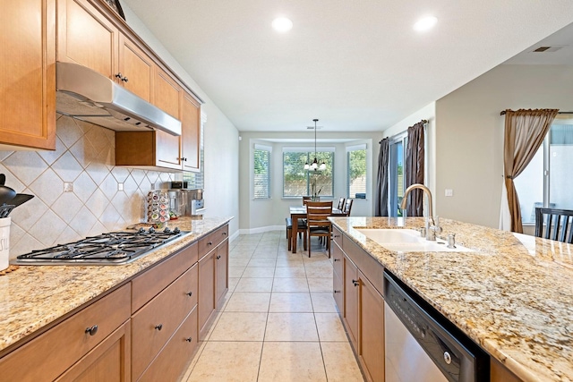 kitchen with sink, hanging light fixtures, light stone counters, and stainless steel appliances