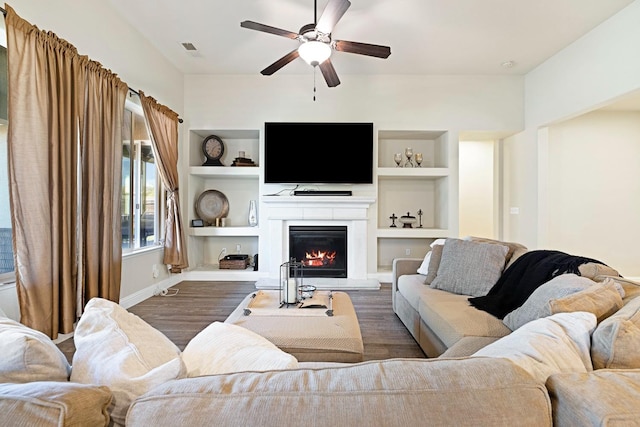 living room with wood-type flooring, built in features, and ceiling fan