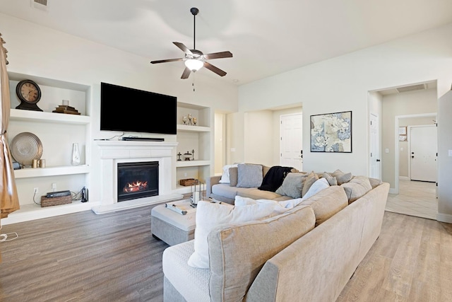 living room with ceiling fan, light hardwood / wood-style floors, and built in shelves