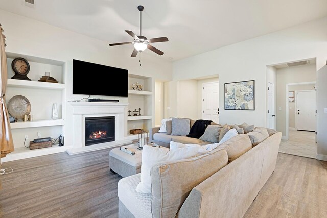 3313 Whiteash Ave, Clovis, CA 93619 - living area with built in features, a ceiling fan, a glass covered fireplace, wood finished floors, and baseboards