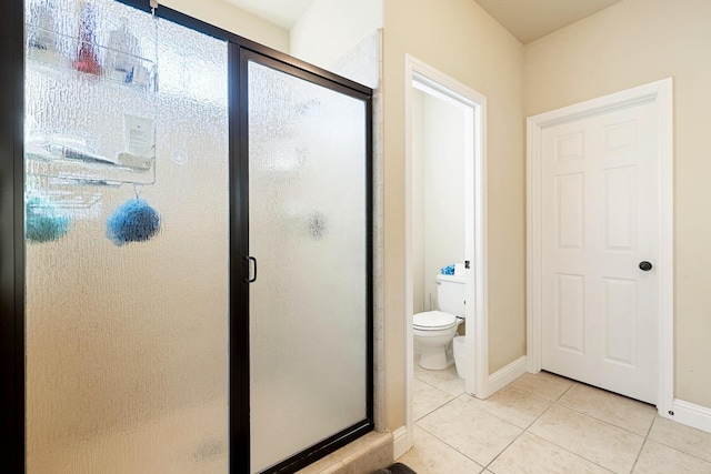 bathroom with toilet, tile patterned floors, and a shower with door