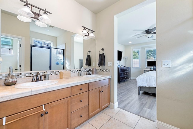 bathroom with decorative backsplash, ceiling fan, hardwood / wood-style flooring, a shower with shower door, and vanity