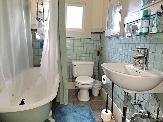 bathroom with tile walls, sink, toilet, and tile patterned flooring