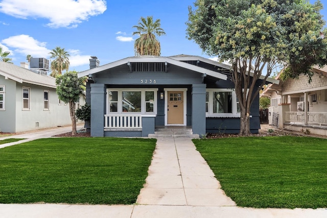 view of front of property featuring central AC, covered porch, and a front yard