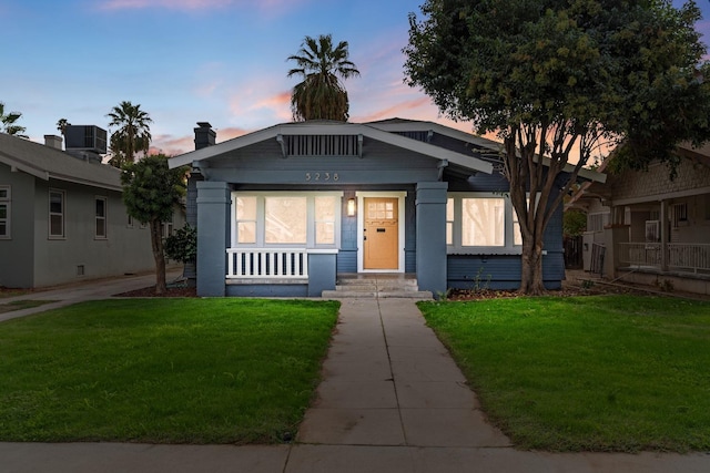 view of front of house with a yard and central air condition unit