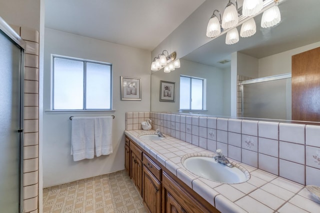 bathroom with vanity, tasteful backsplash, a wealth of natural light, and a shower with shower door