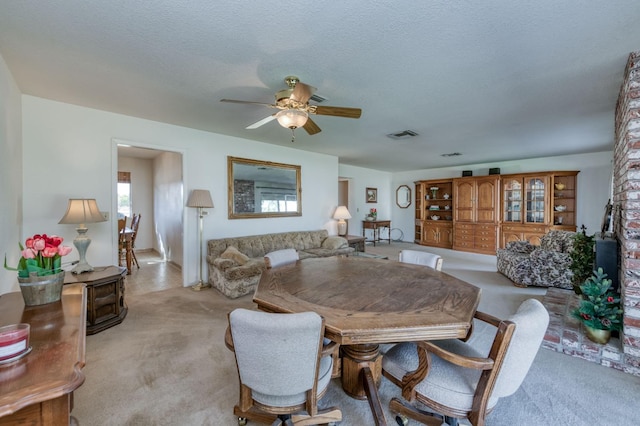 dining space with light carpet, a textured ceiling, and ceiling fan