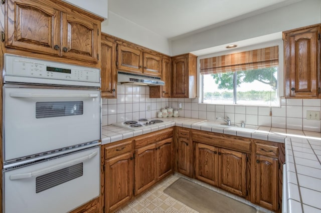 kitchen featuring tile counters, backsplash, and white appliances