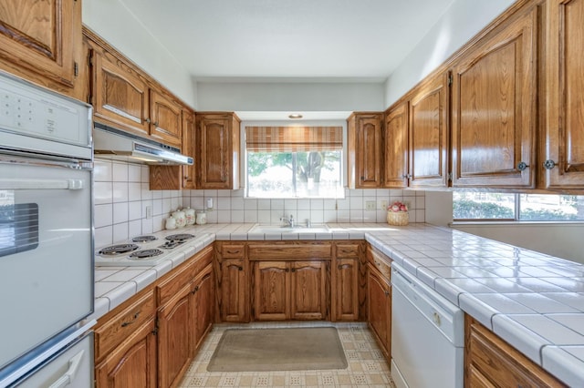 kitchen featuring tile countertops, sink, white appliances, and tasteful backsplash