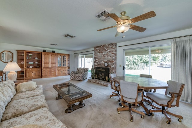 living room featuring ceiling fan, a brick fireplace, and light colored carpet