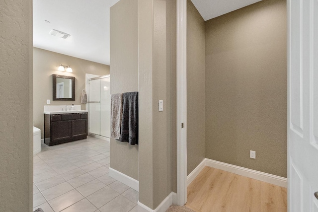 interior space with vanity, hardwood / wood-style floors, and a shower with door