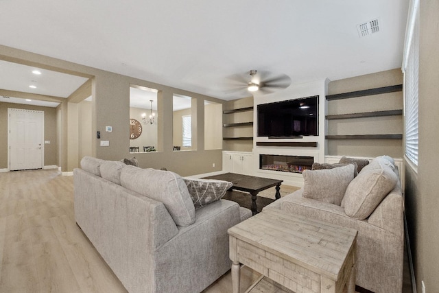 living room with light hardwood / wood-style flooring and ceiling fan with notable chandelier