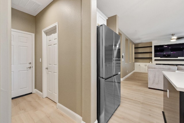 kitchen with stainless steel fridge, white cabinetry, built in features, and light hardwood / wood-style floors