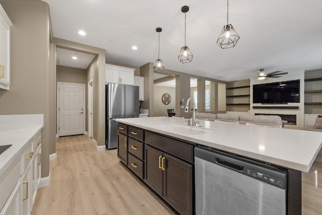 kitchen with a center island with sink, appliances with stainless steel finishes, white cabinetry, decorative light fixtures, and sink