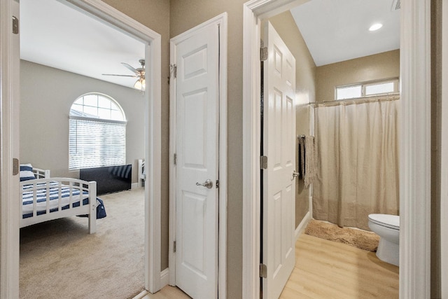 bathroom with a shower with curtain, wood-type flooring, toilet, and ceiling fan