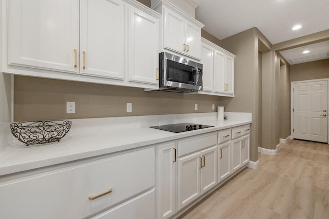 kitchen with white cabinets, light wood-type flooring, and black electric cooktop