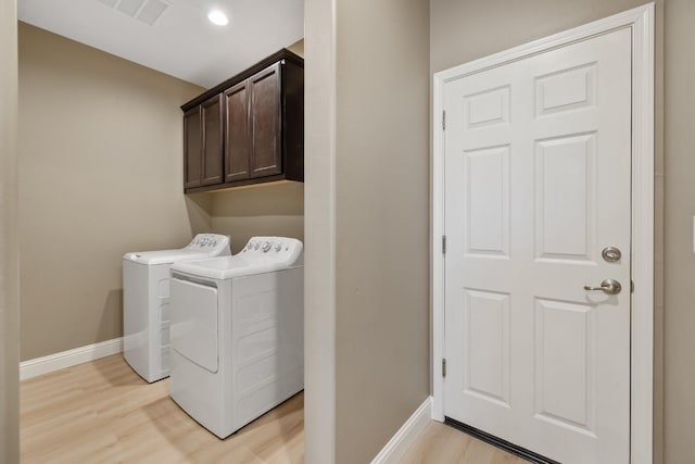 laundry room with light hardwood / wood-style flooring, separate washer and dryer, and cabinets