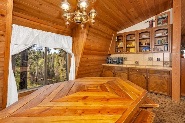 interior space with decorative backsplash, wooden ceiling, vaulted ceiling, an inviting chandelier, and wood walls