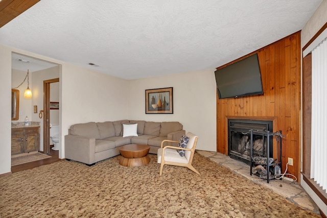 living room with wooden walls, a textured ceiling, and light hardwood / wood-style floors