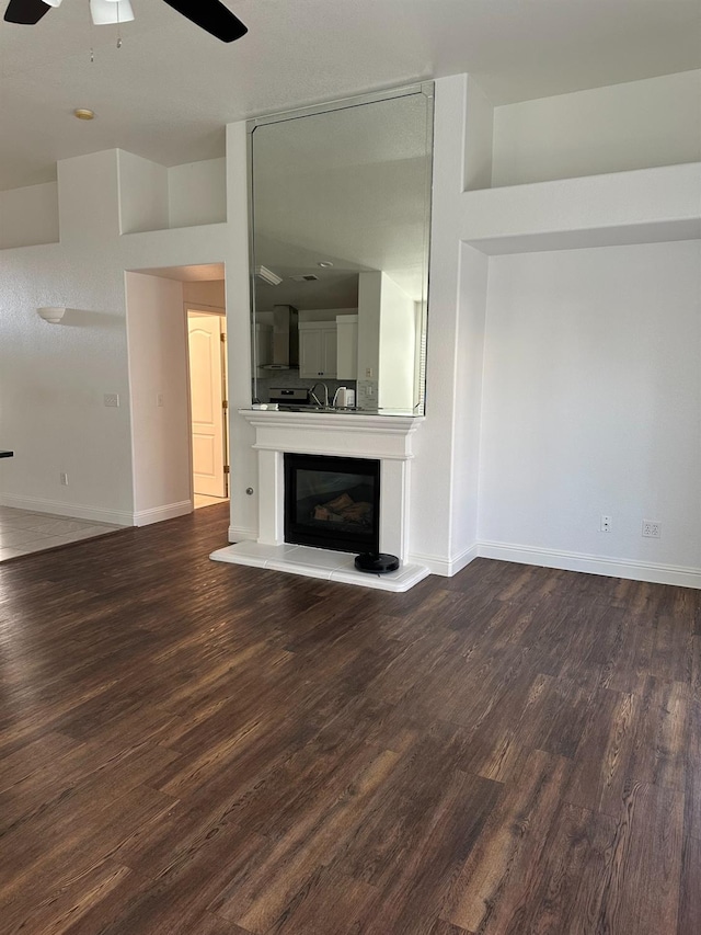 unfurnished living room featuring dark wood-type flooring and baseboards