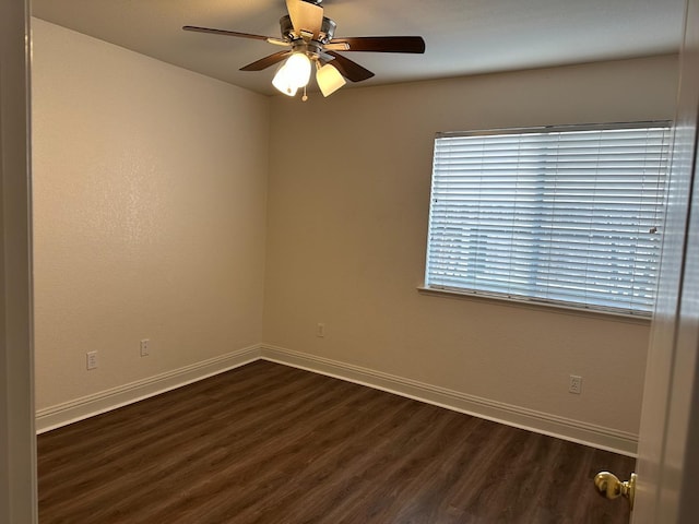 spare room featuring dark wood-style floors, ceiling fan, and baseboards