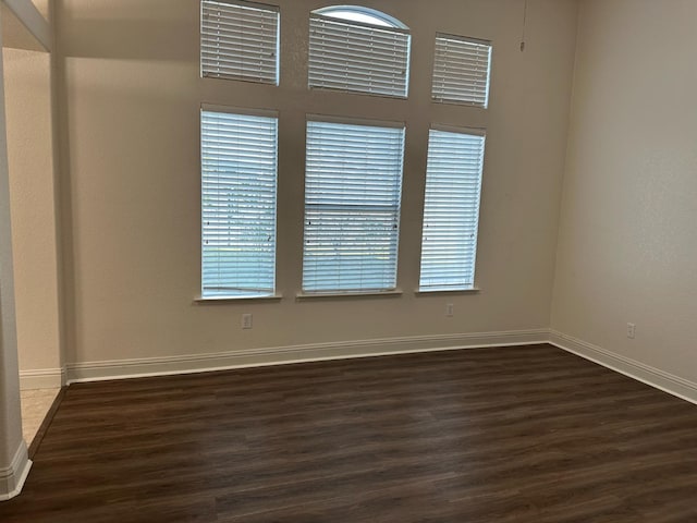 unfurnished room featuring dark wood-style floors and baseboards