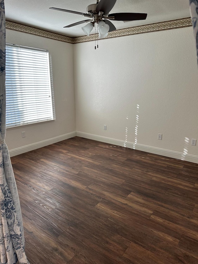 empty room featuring a ceiling fan, dark wood-style flooring, and baseboards