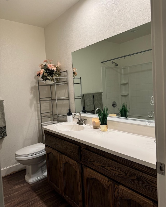 bathroom with vanity, toilet, hardwood / wood-style flooring, and a shower