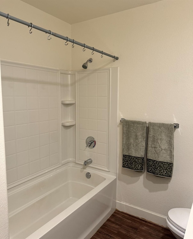 bathroom featuring toilet, wood-type flooring, and tiled shower / bath