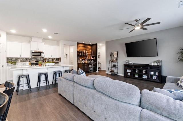 living room featuring ceiling fan and dark wood-type flooring