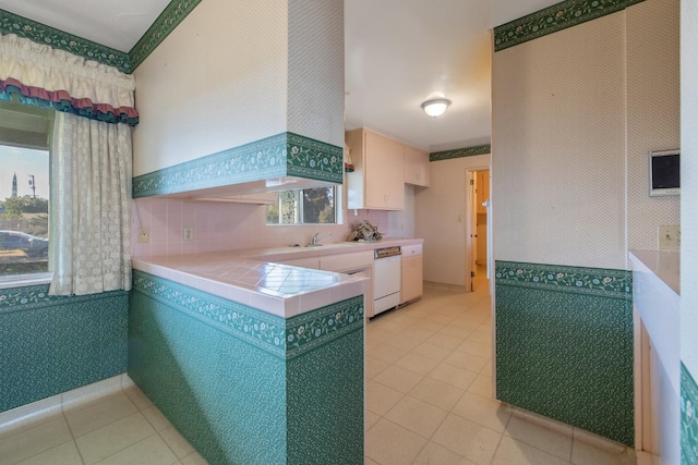 kitchen with sink, dishwasher, tile counters, and light tile patterned floors