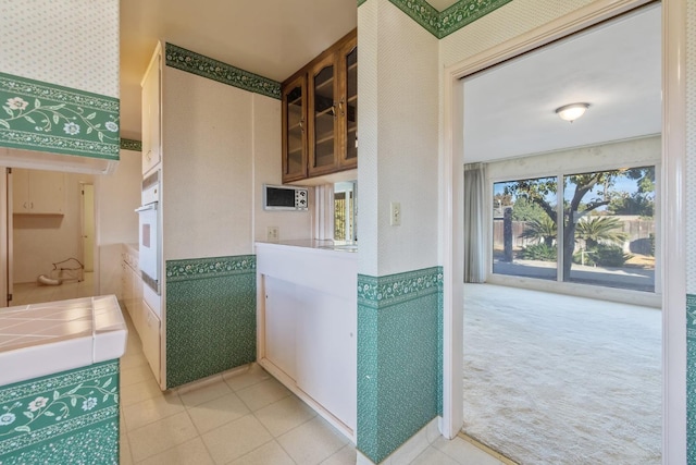 kitchen featuring tile countertops, light carpet, and oven