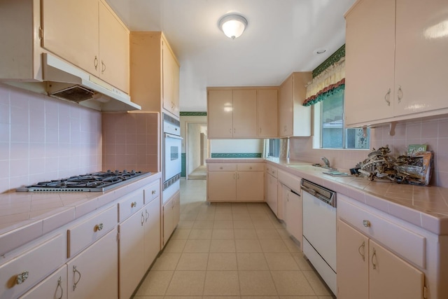 kitchen featuring white appliances, tile countertops, tasteful backsplash, and sink