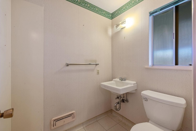 bathroom with toilet, sink, and tile patterned floors