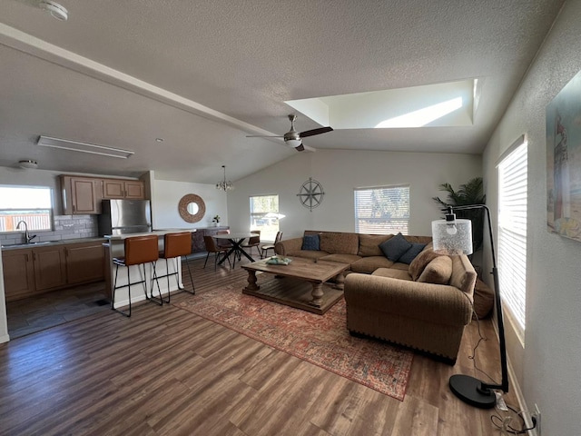 living room with dark hardwood / wood-style floors, sink, lofted ceiling with skylight, a textured ceiling, and ceiling fan