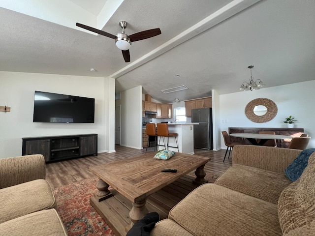 living room featuring vaulted ceiling, a textured ceiling, ceiling fan with notable chandelier, and dark hardwood / wood-style flooring